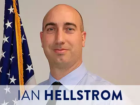 Headshot of Ian Hellstrom, FAA, with American flag in the background. 